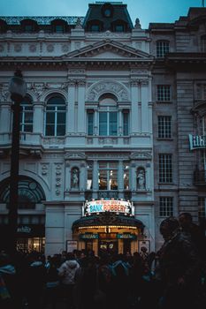 Crowded street in front of London's Criterion Theatre showcasing 'Bank Robbery' play at night.