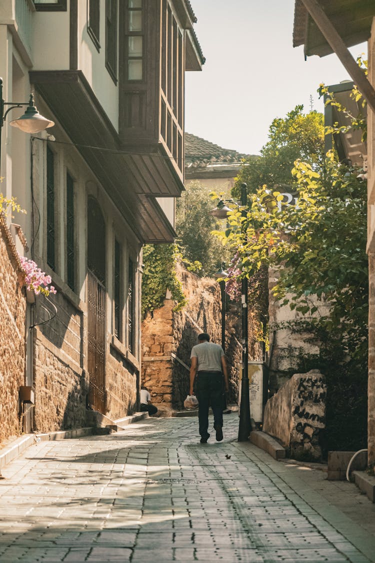 Man In Gray Crew Neck Shirt Walking On Alley