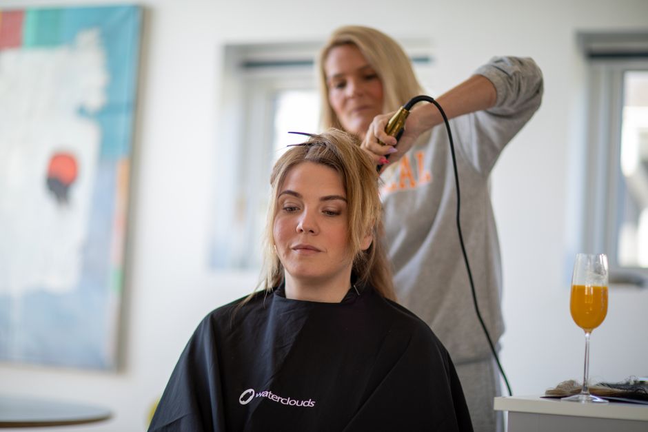 A woman gets her hair styled with a curling iron in a contemporary salon setting.