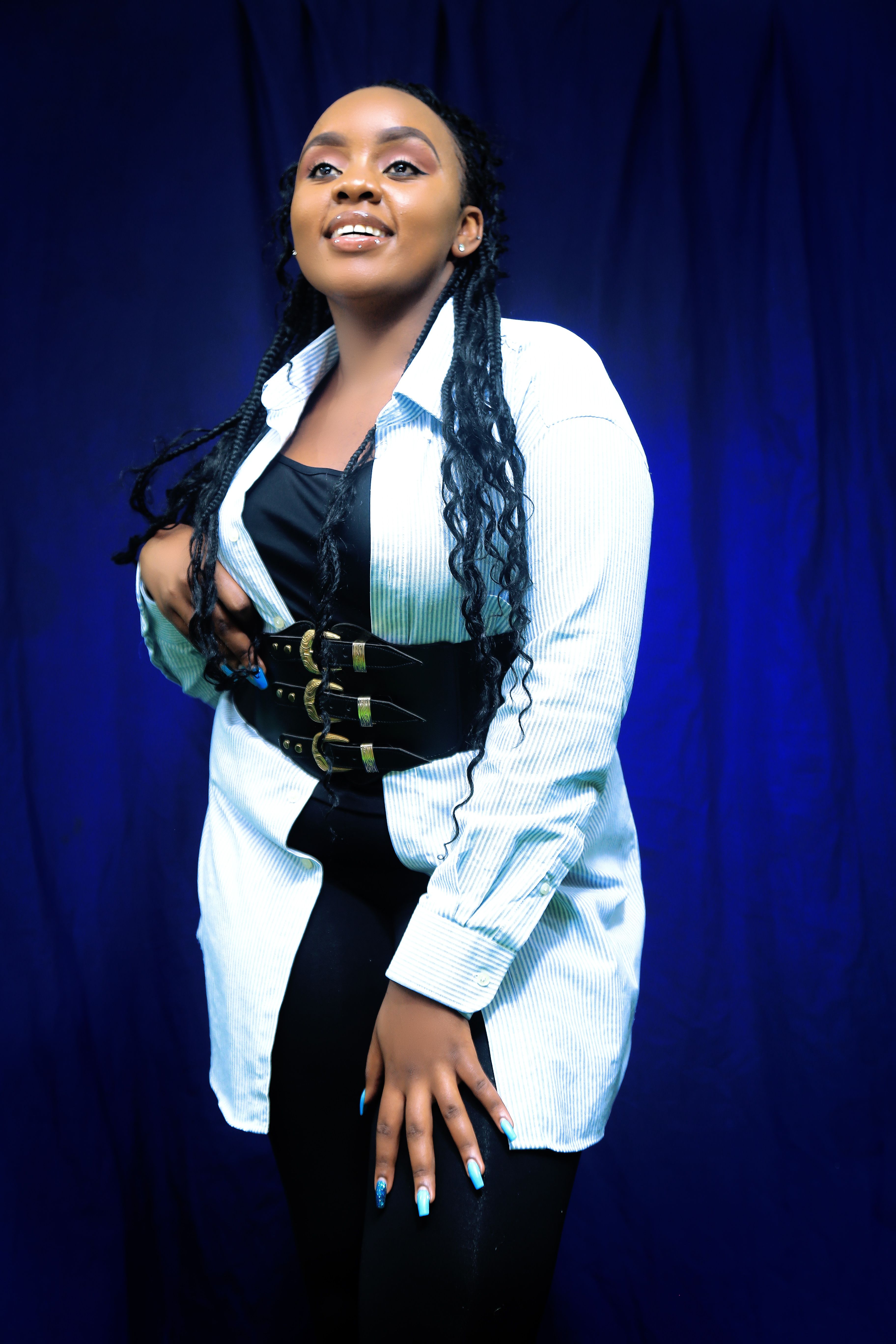 A stylish African American woman poses confidently in a studio setting.