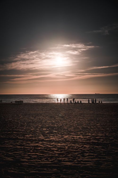 Free Silhouetted people enjoy a serene sunset at Virginia Beach, capturing the natural beauty of the ocean and sky. Stock Photo