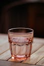 特写镜头聚焦于木桌上盛有液体的时尚粉色玻璃，尽显优雅