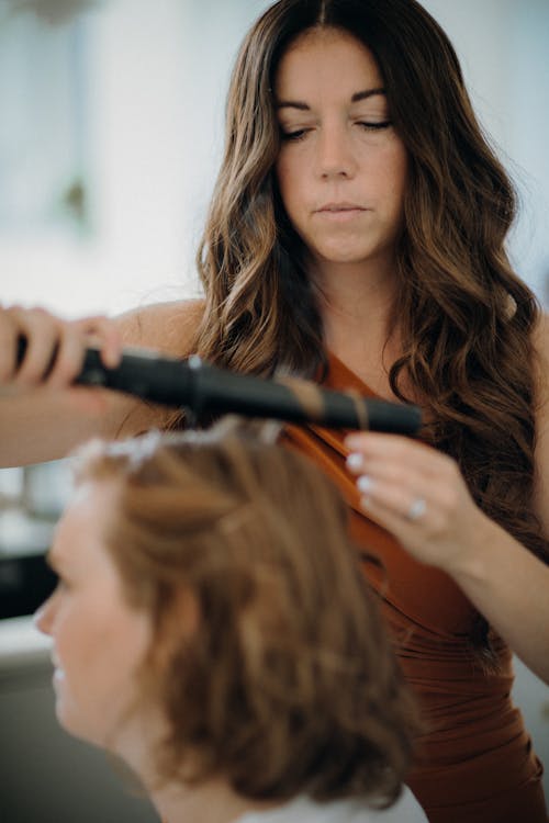 Hairdresser Curling Womans Hair with an Electric Roller