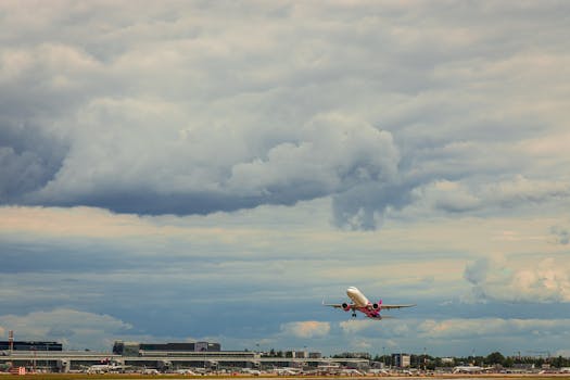 Airplane departing from airport under dramatic cloudy sky, ideal for travel themes.