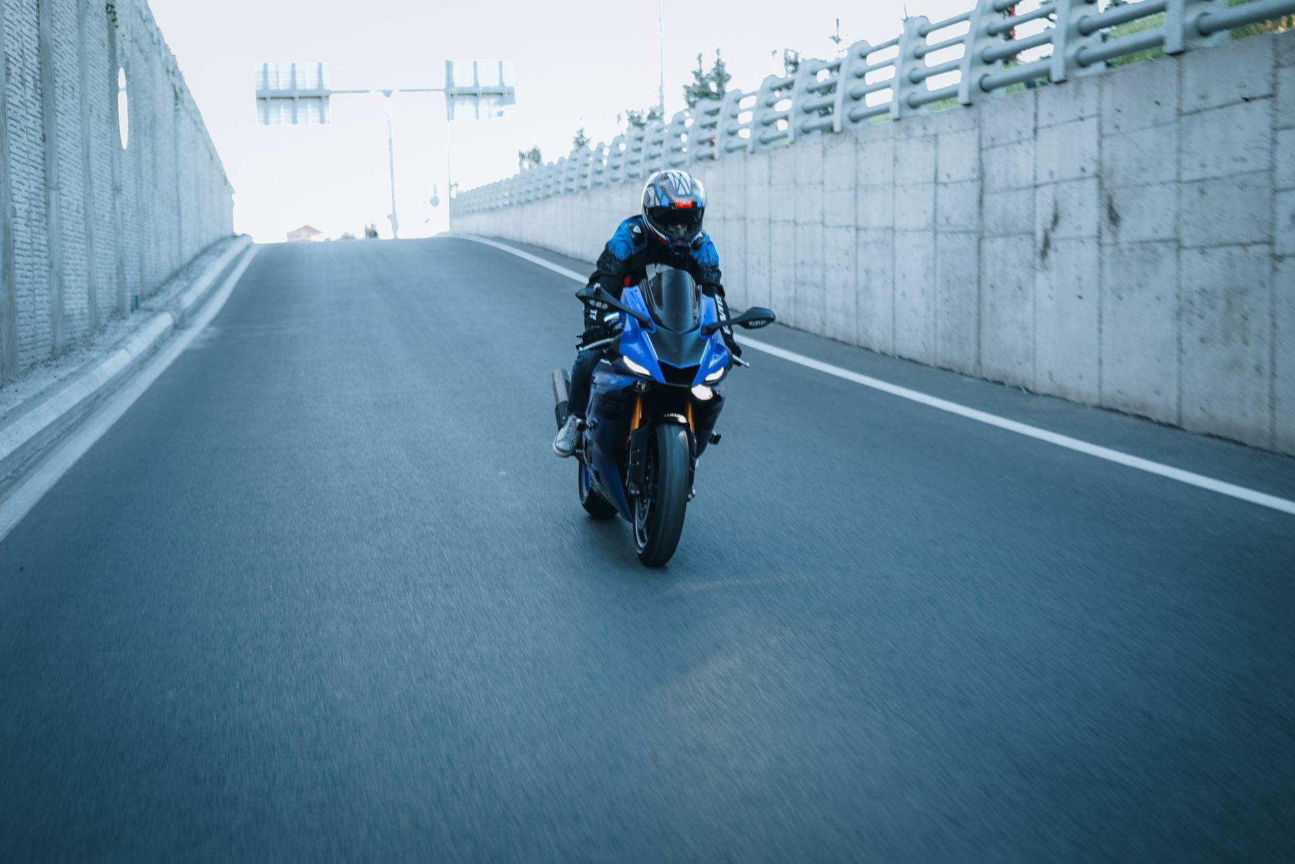 A motorcyclist in a helmet rides down a paved highway road.
