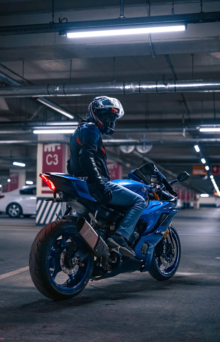 Person Wearing A Motorcycle Helmet On A Blue Sports Bike