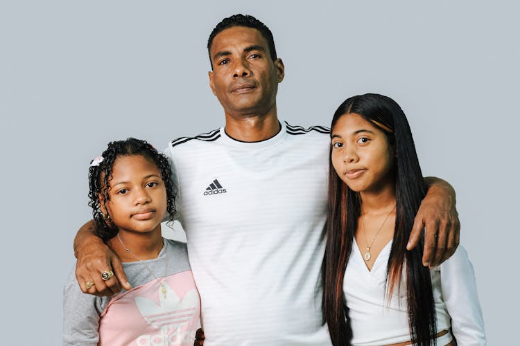 Man Posing With Daughters In Studio