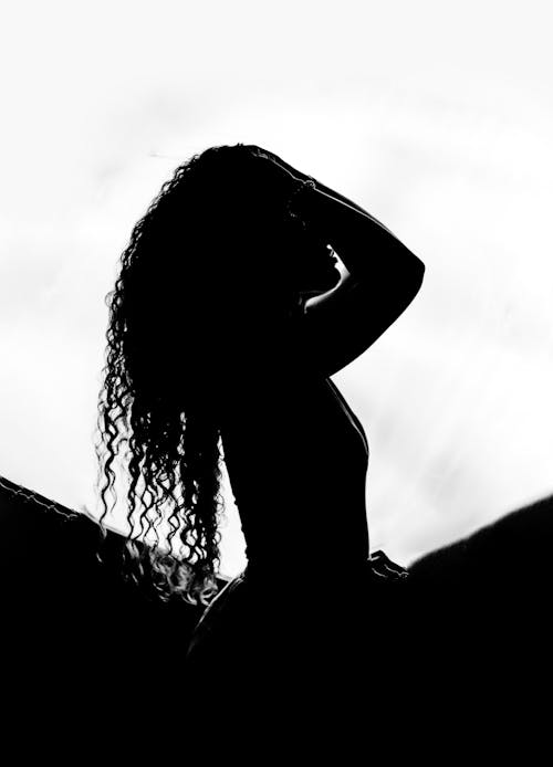 Grayscale Photo of Woman Touching Her Hair