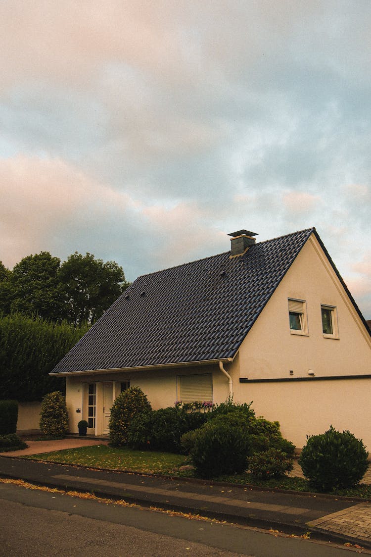 A House With Roof Tiles Along A Road Under A Cloudy Sky