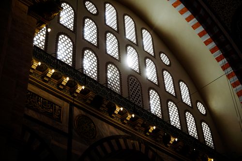 Free Sunlight streams through arched windows in a mosque, showcasing intricate designs. Stock Photo