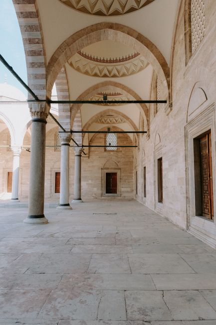 Elegant arched stone architecture with wooden doors and pillars in an outdoor setting.