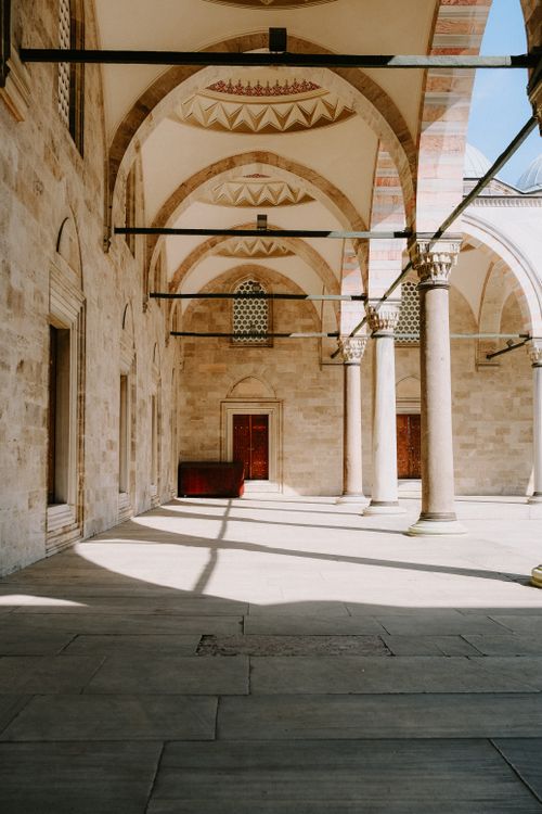 Free A serene view of an old stone archway with columns in a historic building. Stock Photo