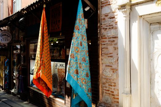 Vibrant scarves hanging outside a store, showcasing cultural textiles.