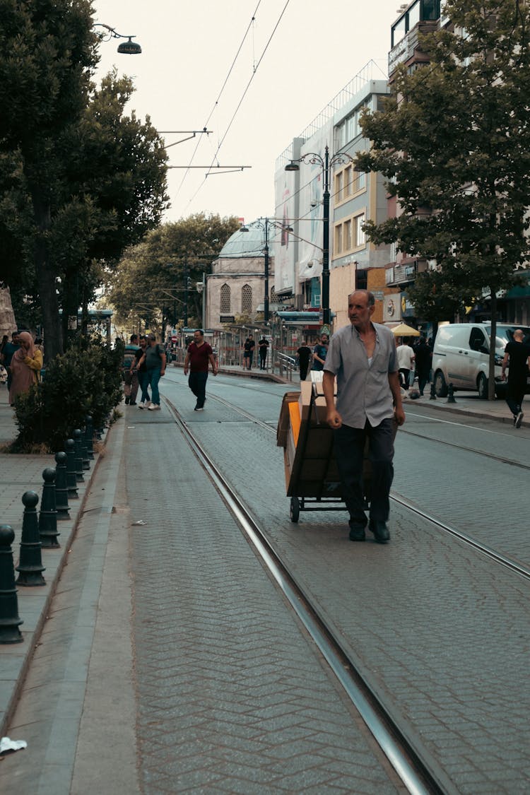 Man Walking On Railroad Pulling A Hand Truck Carrier With Boxes