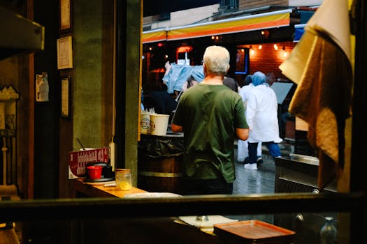 A vibrant market scene with a vendor observing customers outdoors in a city setting.
