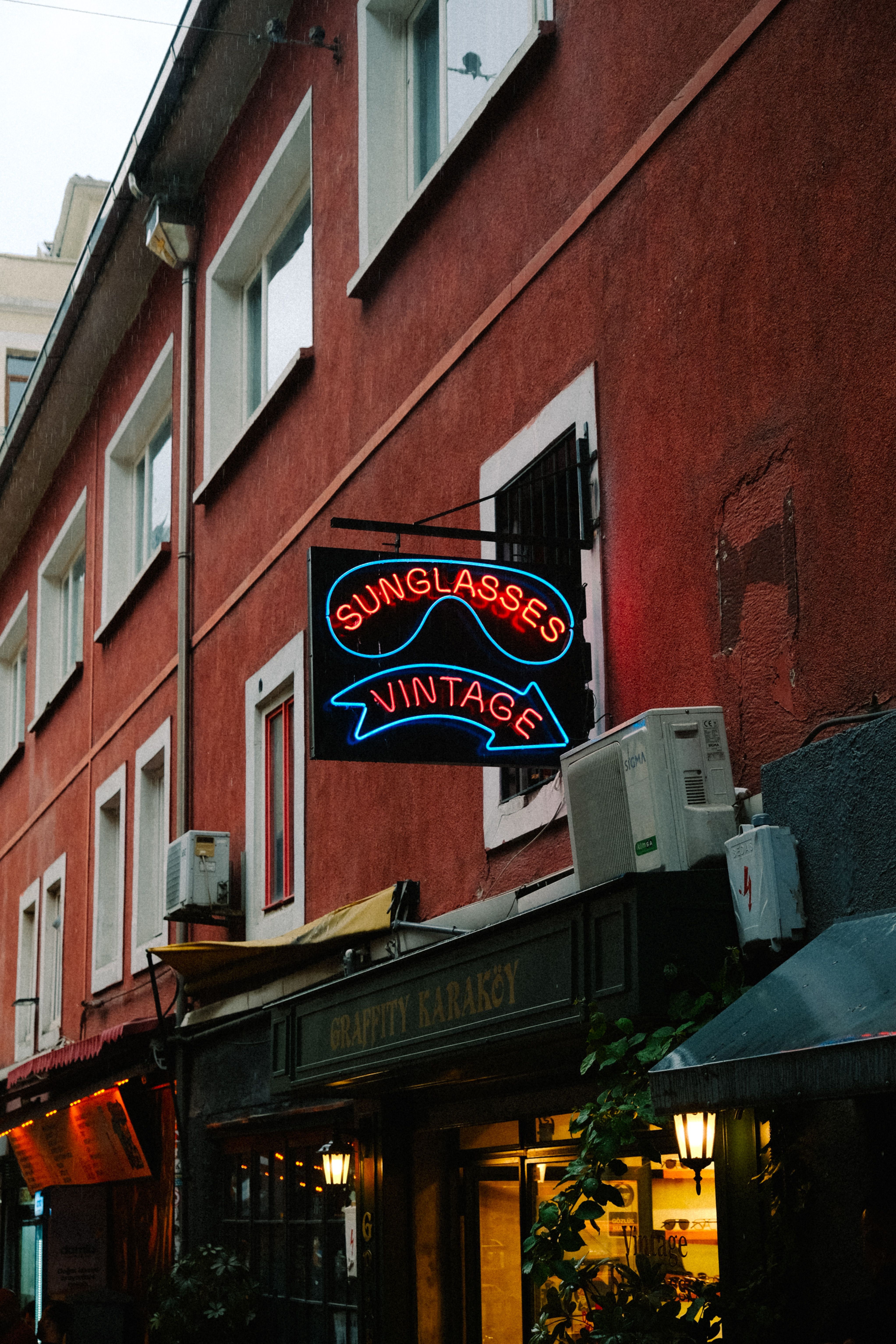 A stylish vintage store sign for sunglasses on a vibrant urban building exterior, creating a retro city vibe.