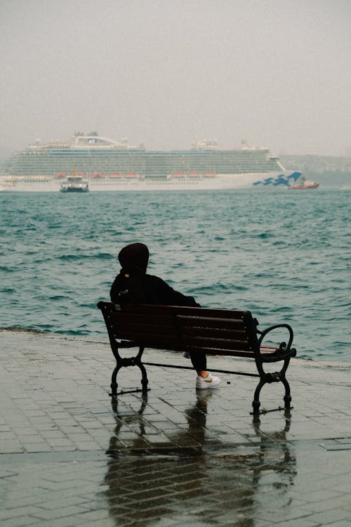 Person Sitting on Bench by Sea Shore