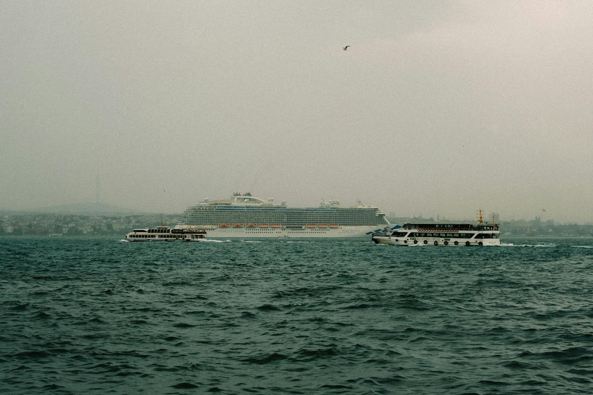 Serene ocean view featuring a large cruise ship and ferry boats under a misty sky.