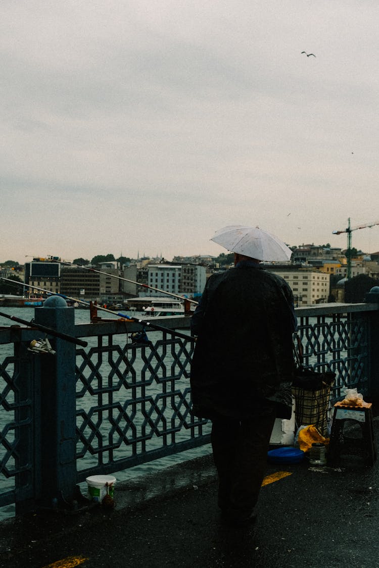 Backview Of Person With Umbrella Hat Fishing On A River 