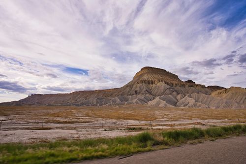Free Expansive landscape with a prominent rocky mountain under vibrant cloud-filled sky. Stock Photo