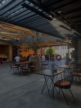 Chic outdoor restaurant area featuring modern architecture, tables, and seating.