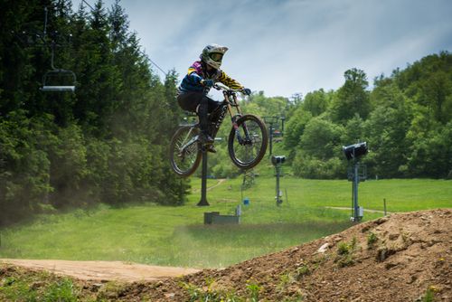 Free A cyclist performs a jump on an off-road mountain trail, showcasing extreme biking skills and adventure. Stock Photo