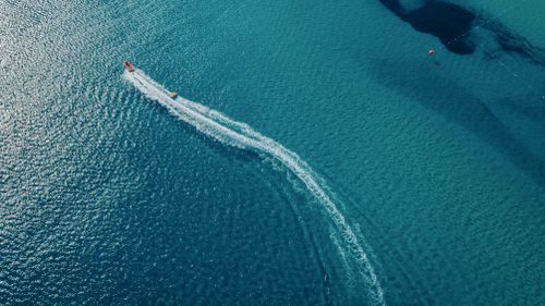 Free A scenic aerial view capturing a motorboat cruising through the clear blue waters of Alaçatı, Izmir, Turkey. Stock Photo