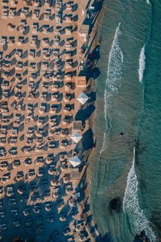 Stunning aerial shot of Alaçatı beach showcasing rows of umbrellas and gentle sea waves.