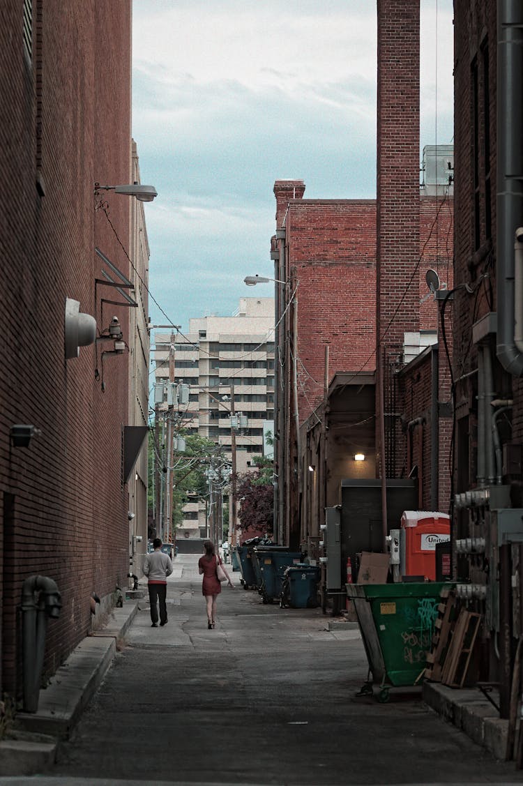 People Walking Alley Near City Brick Buildings