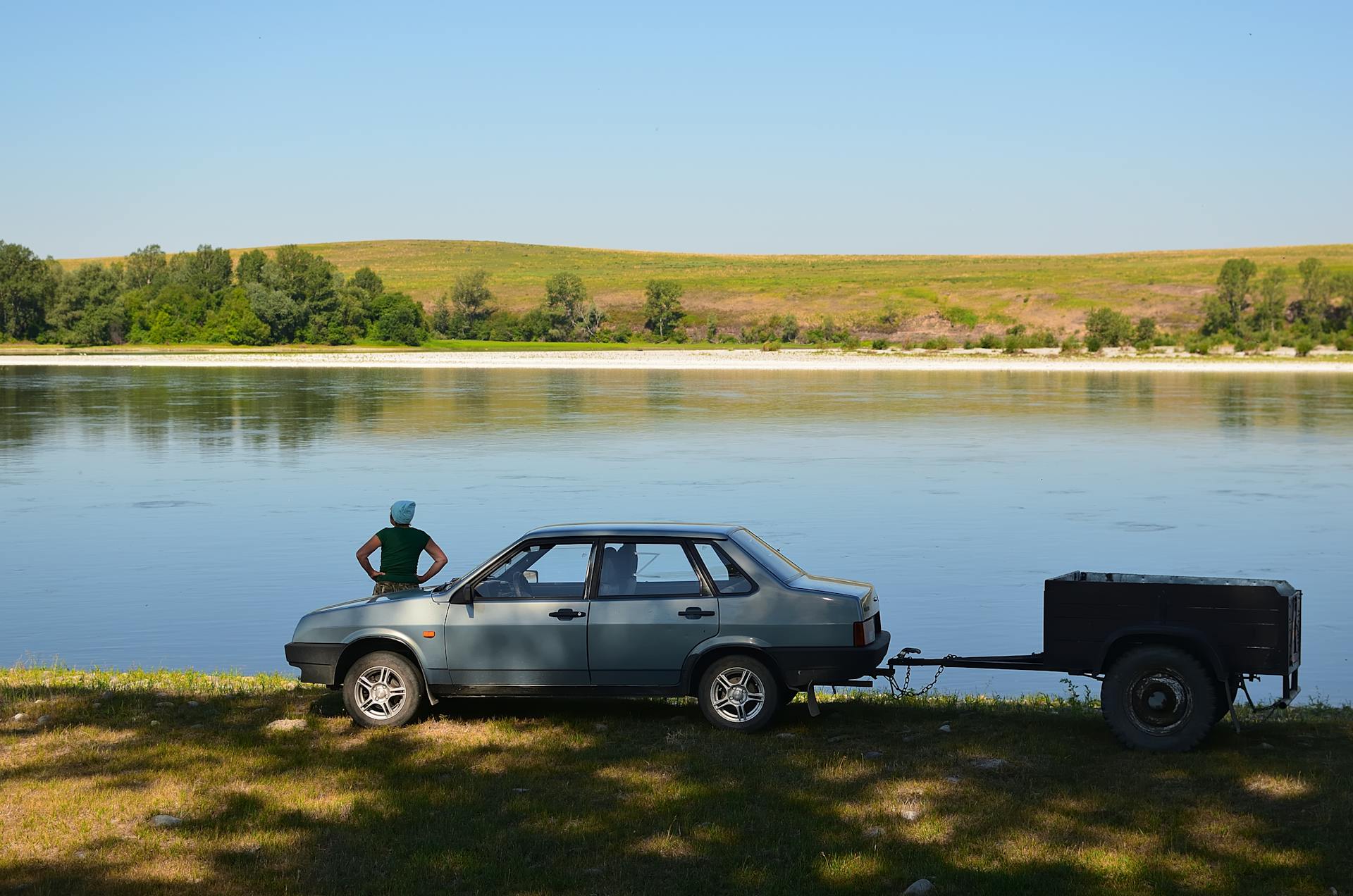 Woman with Car with Trailer on Riverbank