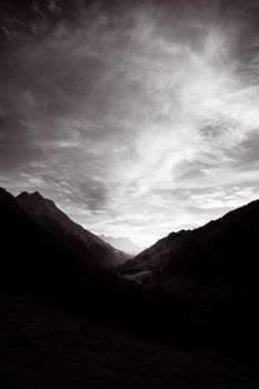 A breathtaking black and white image capturing clouds over a serene mountain valley.