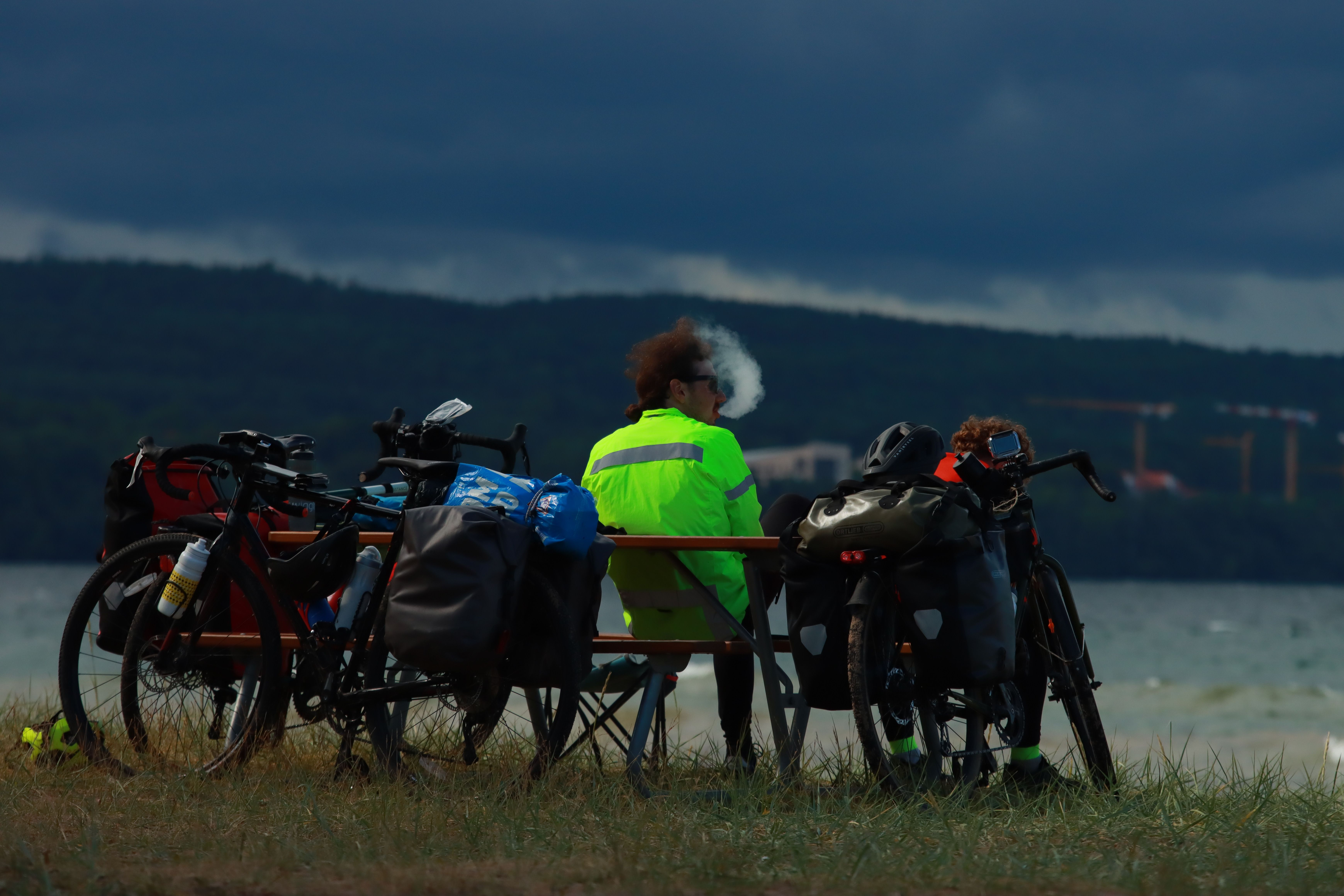 Two cyclists with mountain bikes relax by a lake in Jönköping, Sweden. Overcast skies.