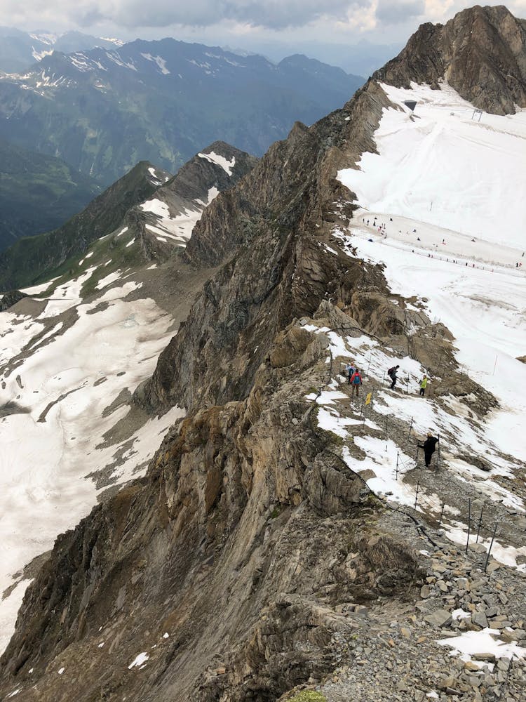 Aerial Photography Of Hikers On Mountain Summit With Snow Covered Ground