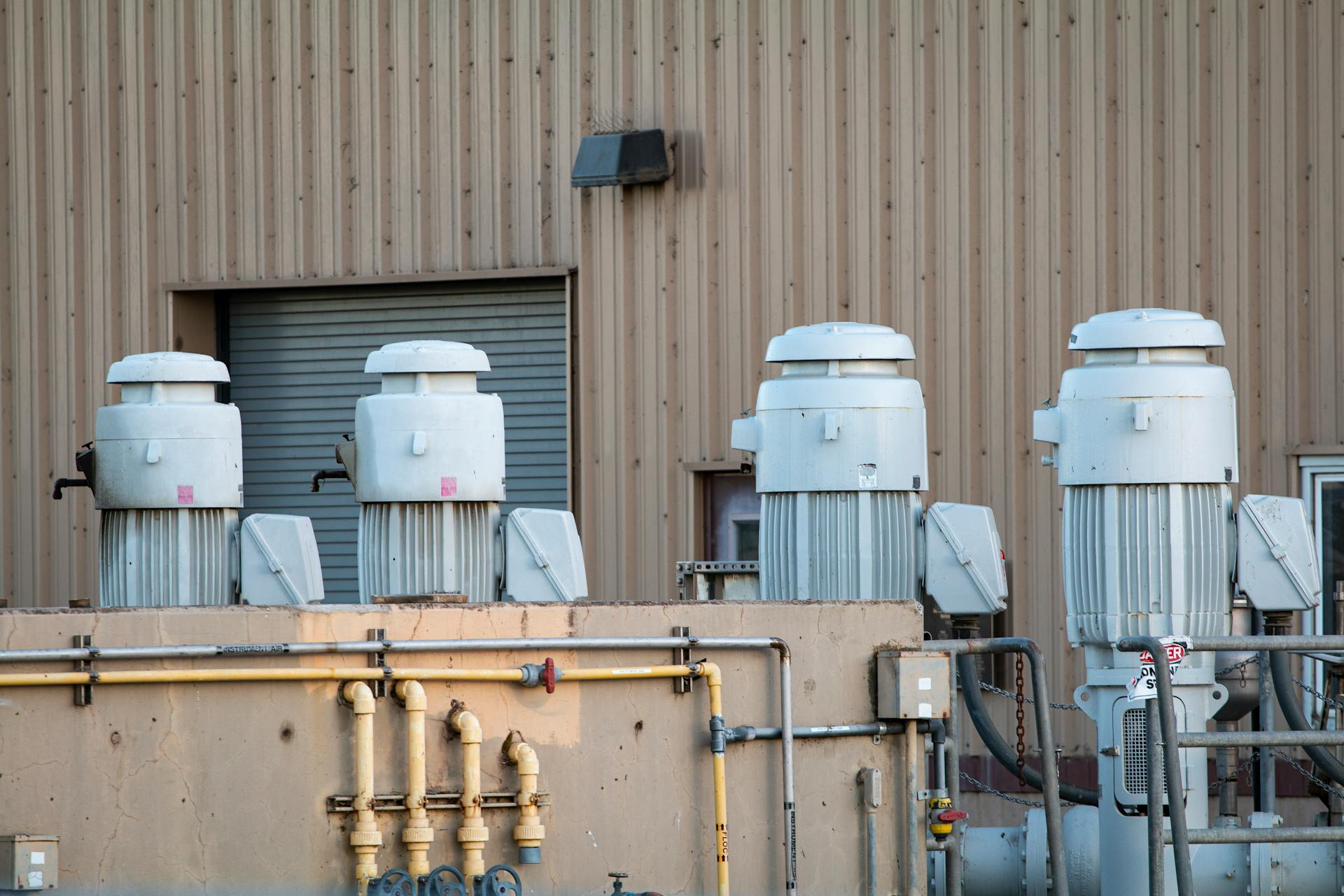 Industrial building facade with large machinery components and pipes visible.