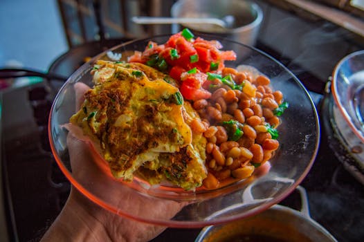 Delicious omelet served with beans and fresh salsa on a clear plate.