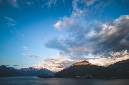 Free Stunning view of mountains and lake under a vibrant blue sky with clouds at sunset. Stock Photo