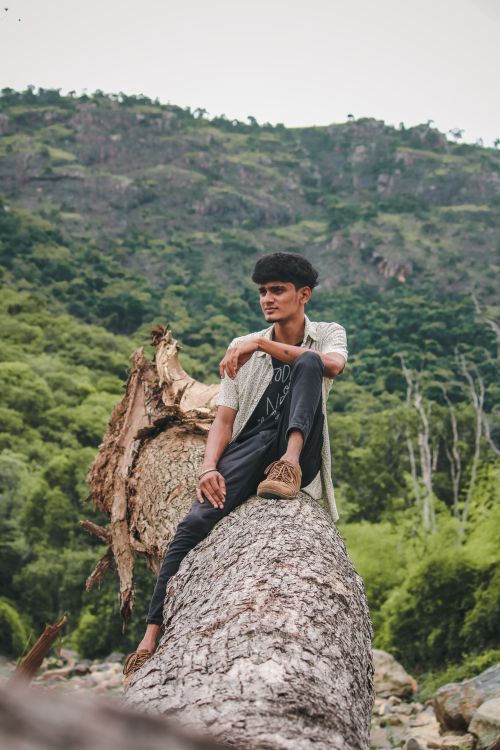 Free Young man sits on a fallen tree in serene Salem, India landscape. Stock Photo