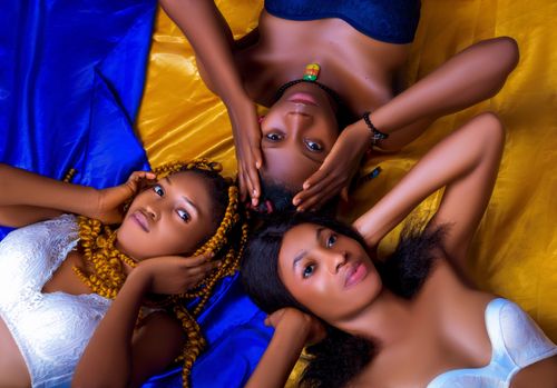 Free Top view of three women in lingerie, lying on vibrant fabrics, creating a dynamic composition. Stock Photo