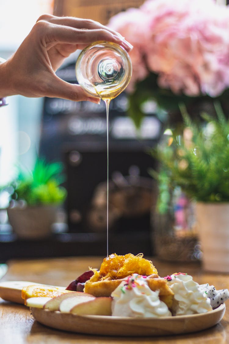 A Person Pouring Honey On A Dish