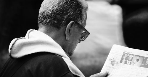 Free Elderly man in glasses reading a newspaper, depicted in a black and white portrait. Stock Photo