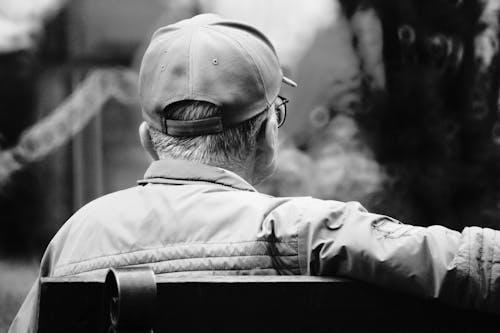 A Grayscale of a Man Sitting on a Bench