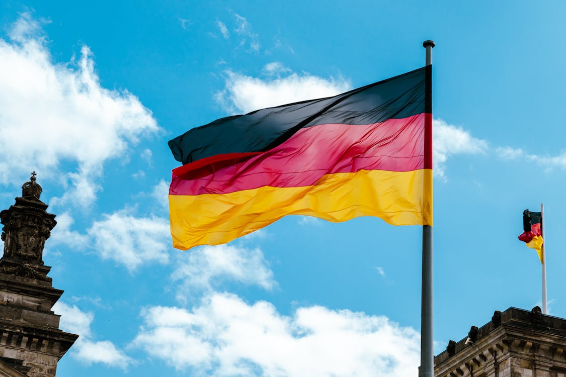 The German Flag Waving On A Flagpole · Free Stock Photo