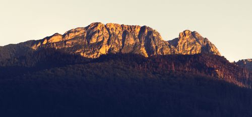 Free Majestic rocky mountain peaks bathed in golden sunset light. Stock Photo