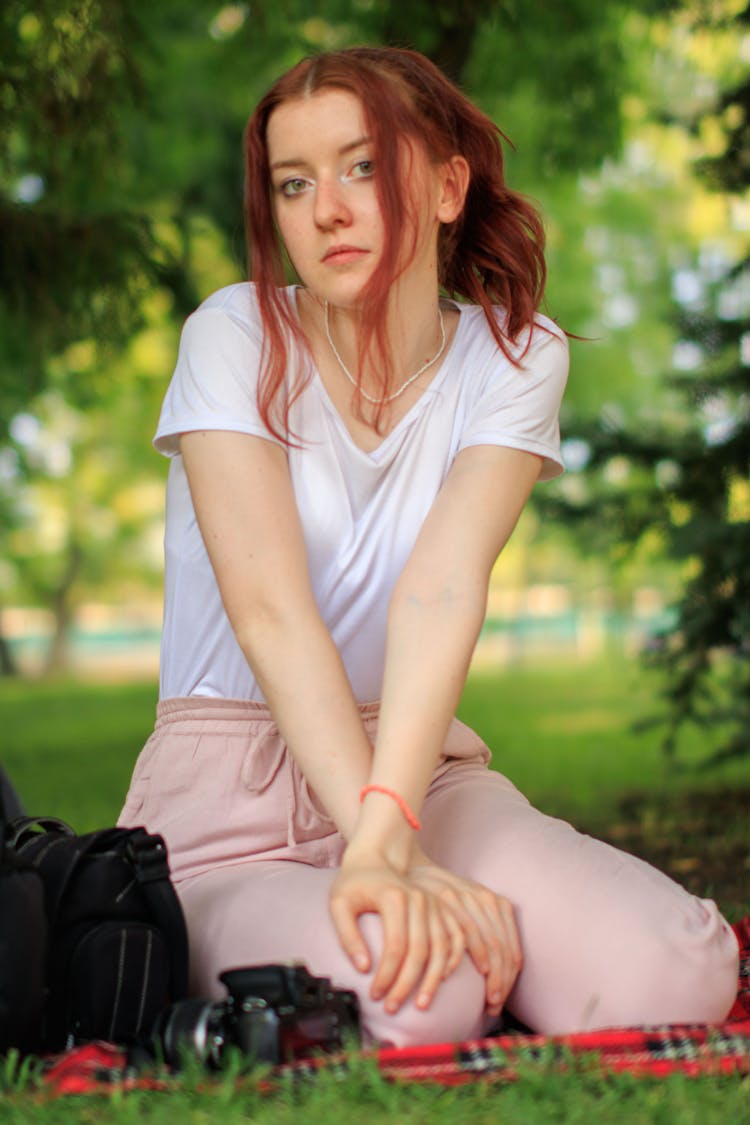 Woman Sitting On The Blanket With A Camera In A Park 