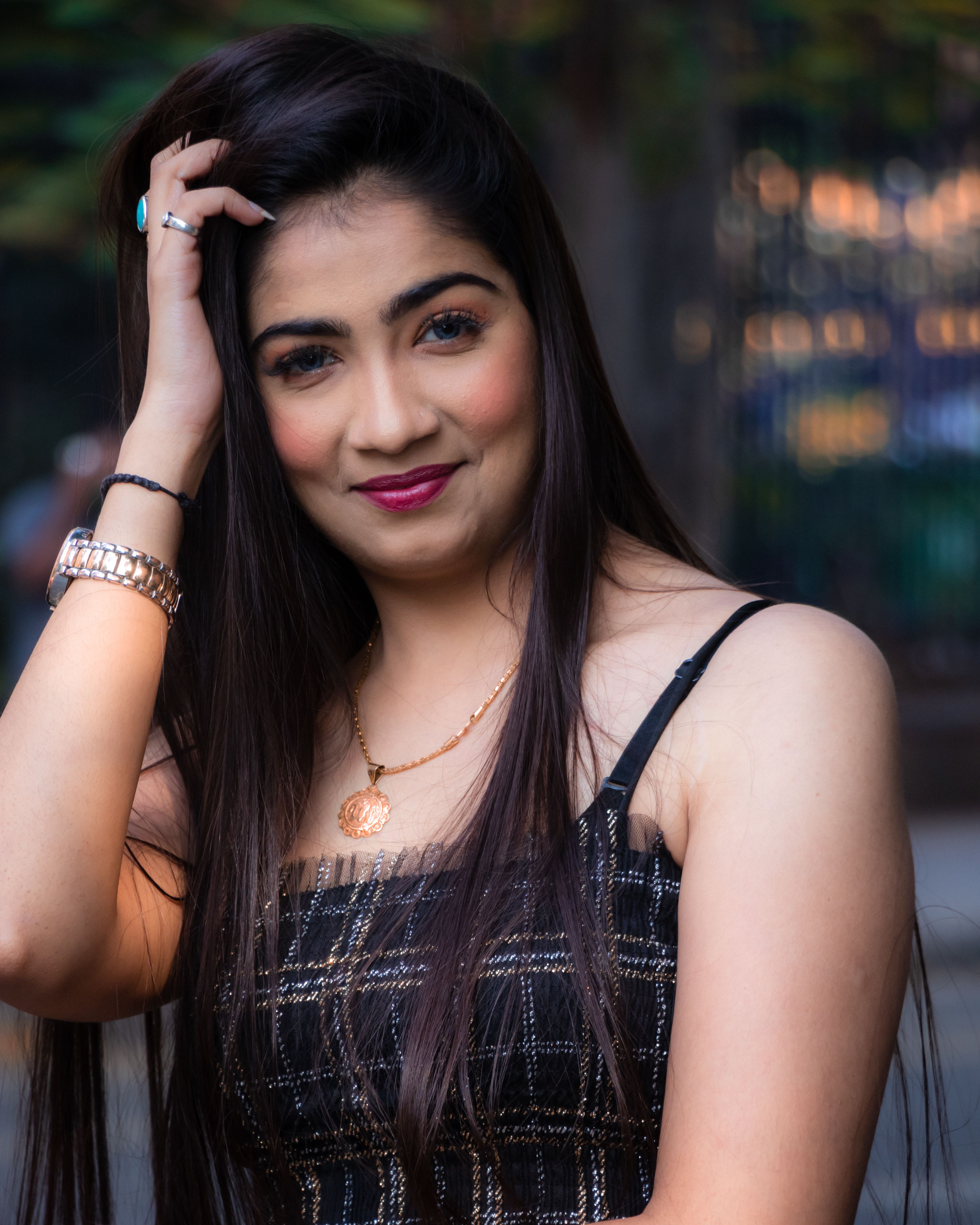 Smiling woman with long hair and striking accessories in an urban outdoor setting.