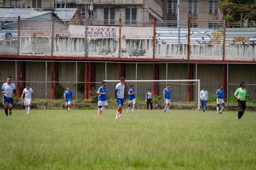 Amateur soccer players compete on an urban field in Venezuela, showcasing teamwork and athleticism.