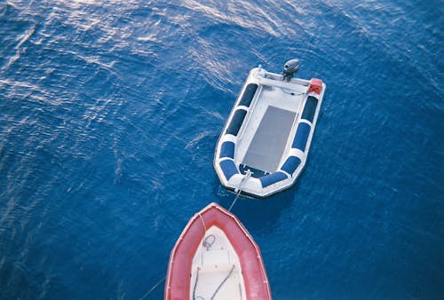 Red Lifeboat Tied to a Blue and White Motorboat 