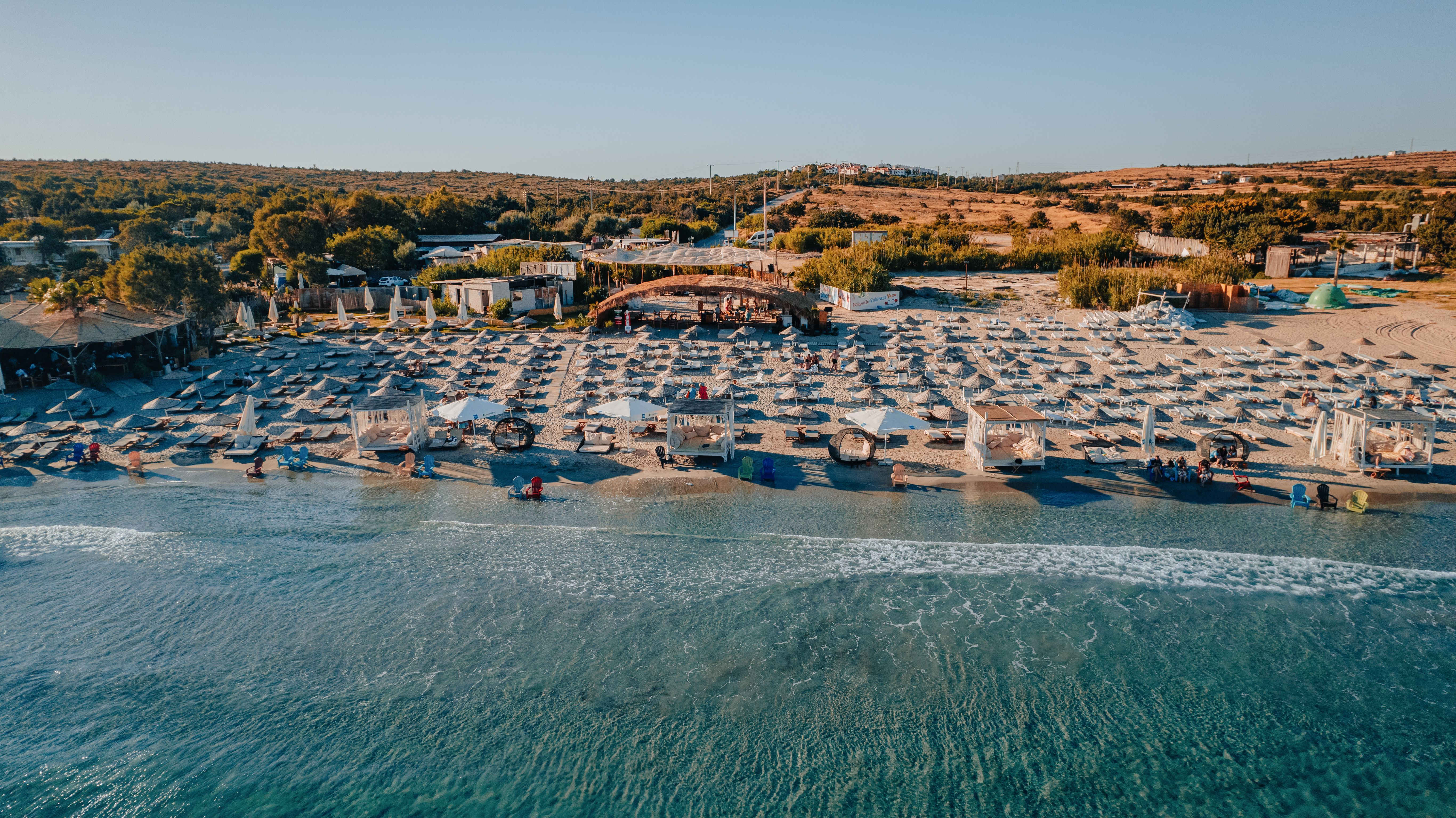 Crystal-clear turquoise waters and white sand beaches of Çeşme at golden hour, İzmir, Turkey, Aegean coastline with windsurfers and pine forests