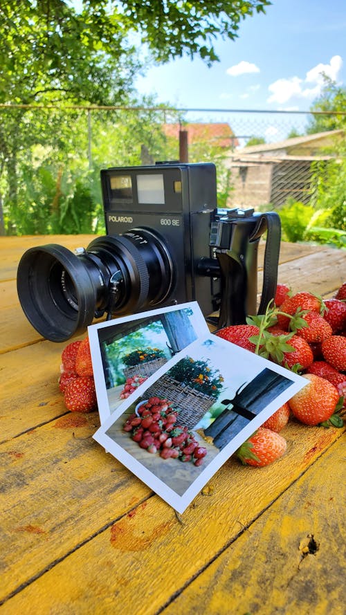 A Polaroid Camera and Strawberries on a Wooden Table
