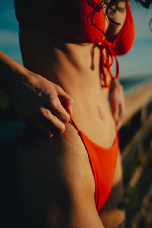 Free Close-up shot of a woman's midsection wearing a red bikini on a sunny day. Perfect for summer and lifestyle themes. Stock Photo
